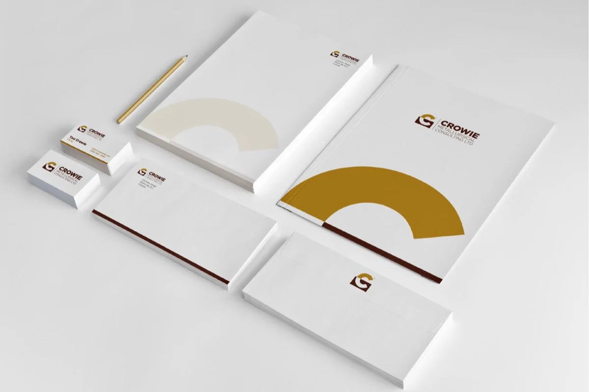 The full Crowie identity system applied to a stationery suite: letterhead, business cards, envelopes, and folders, showing the gold arc and brown details across the full set of touchpoints