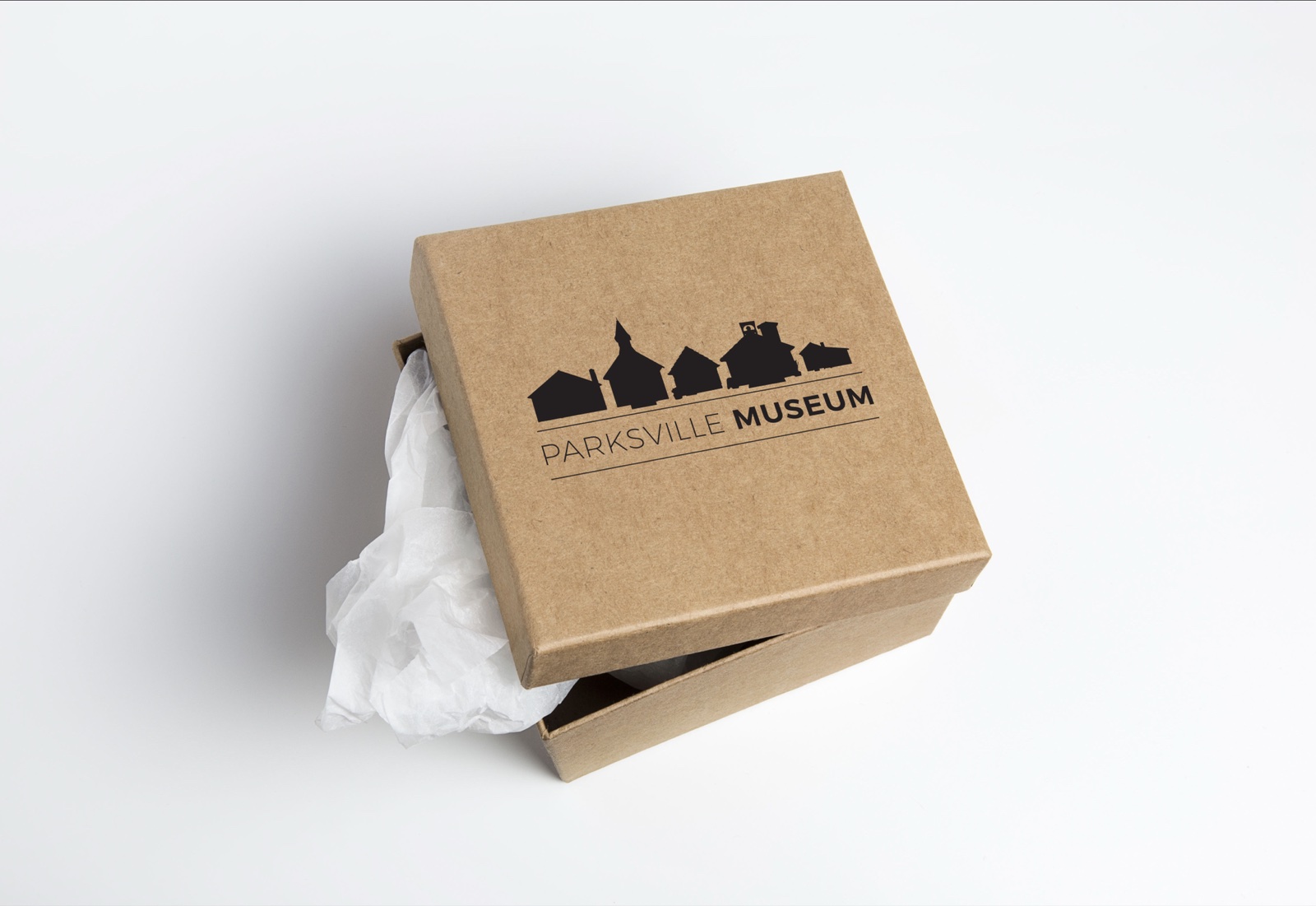 A kraft gift box printed with the Parksville Museum silhouette logo, nestled with tissue paper