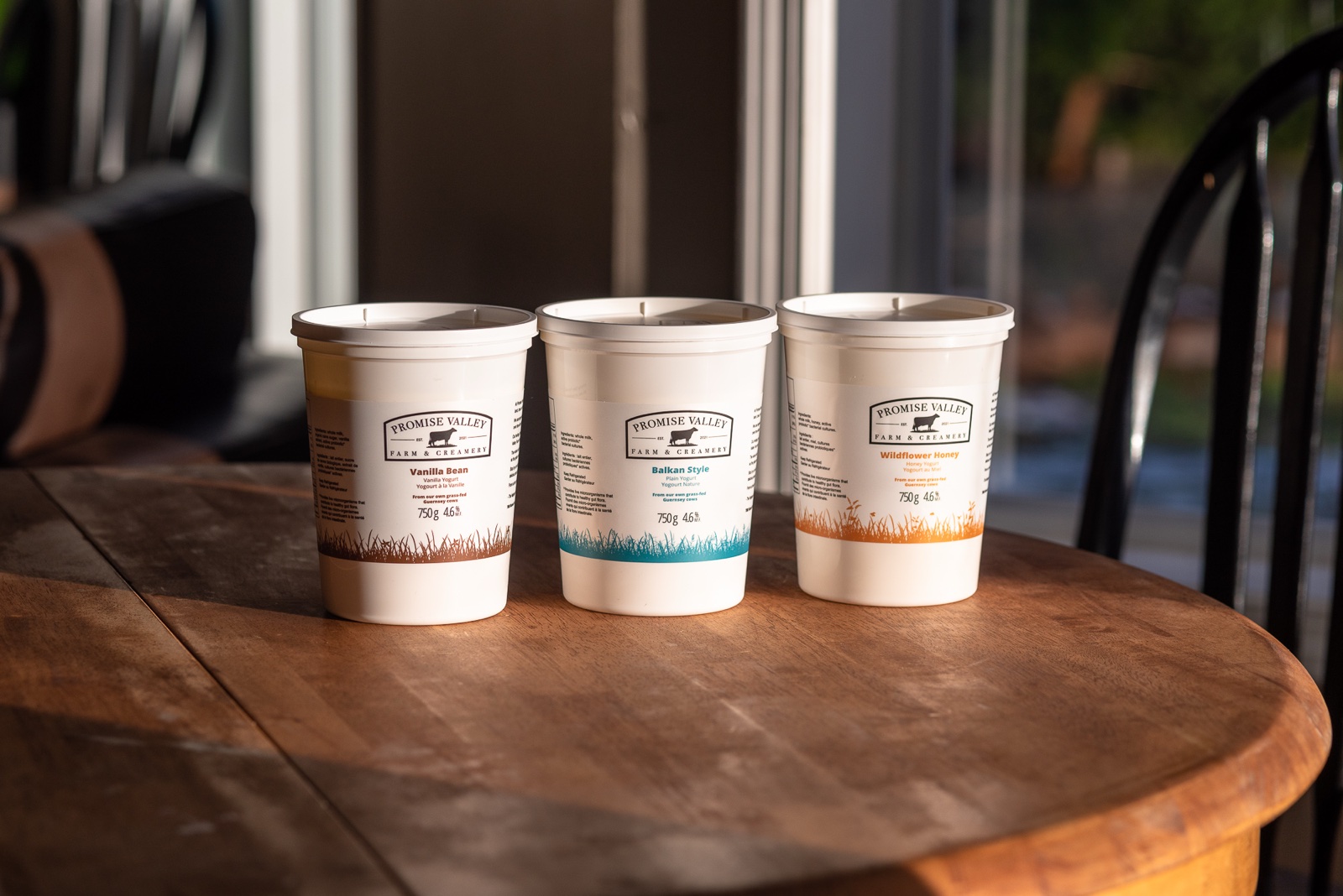 The three Promise Valley Farm yogurt flavours from a lower angle, showing the grass illustrations wrapping around the base of each container